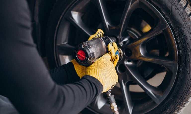 Technician with impact wrench working on tire